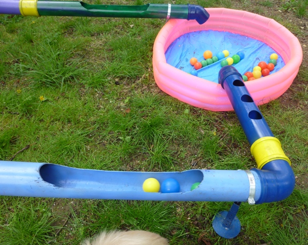 Viele bunte Bällchen schwimmen durch Wasserrohre in verschiedene kleine Swimmingpools.das La